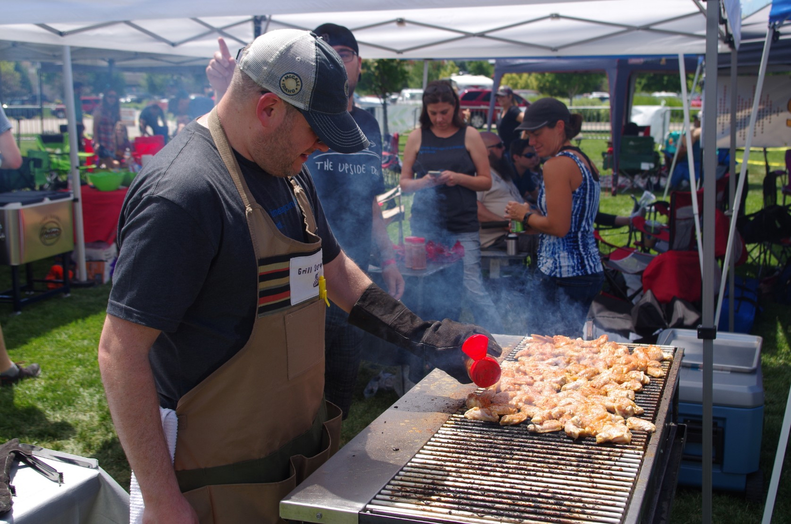 A man cooking chicken wings at an outside grill